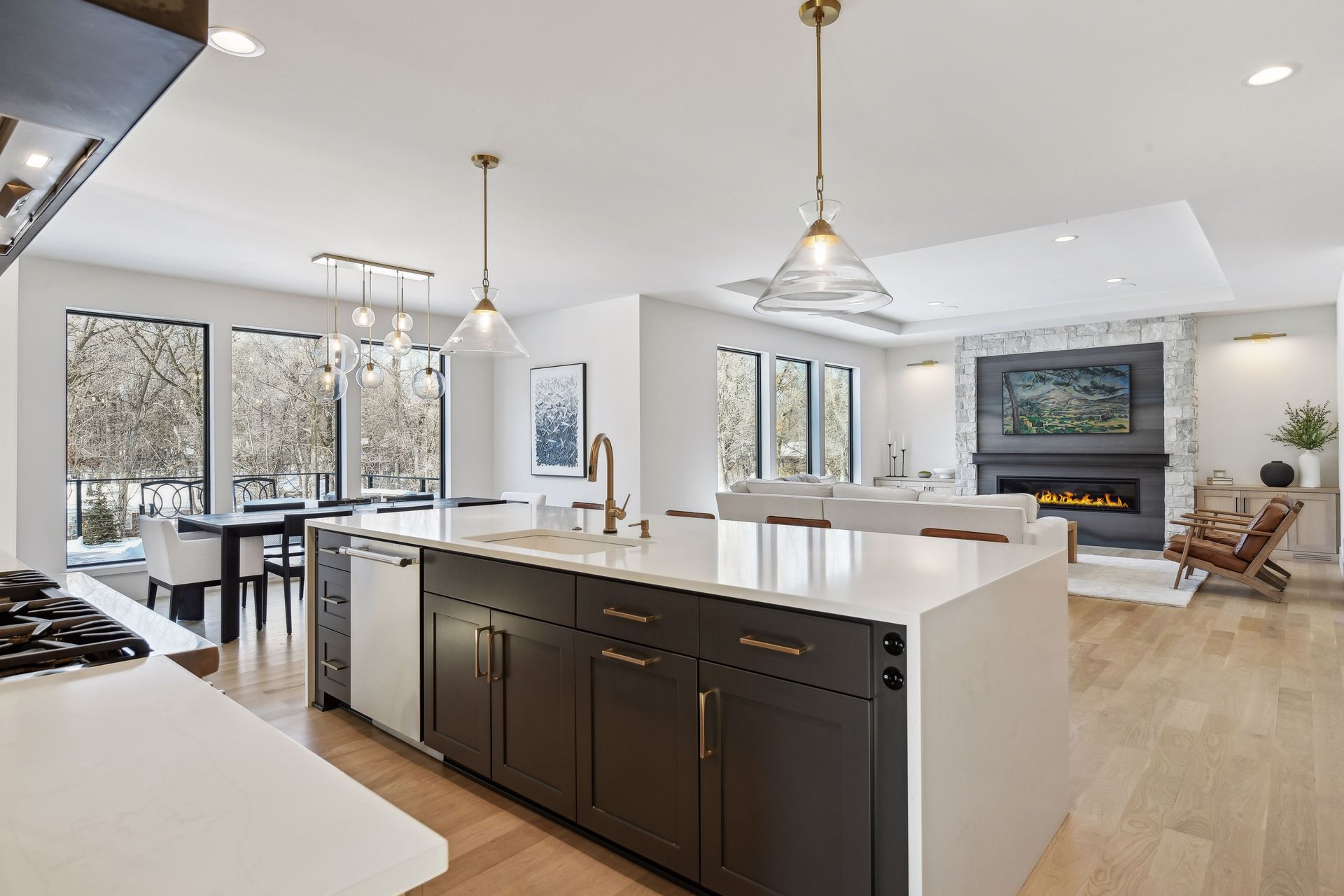 Open concept kitchen flowing into living room with stone fireplace