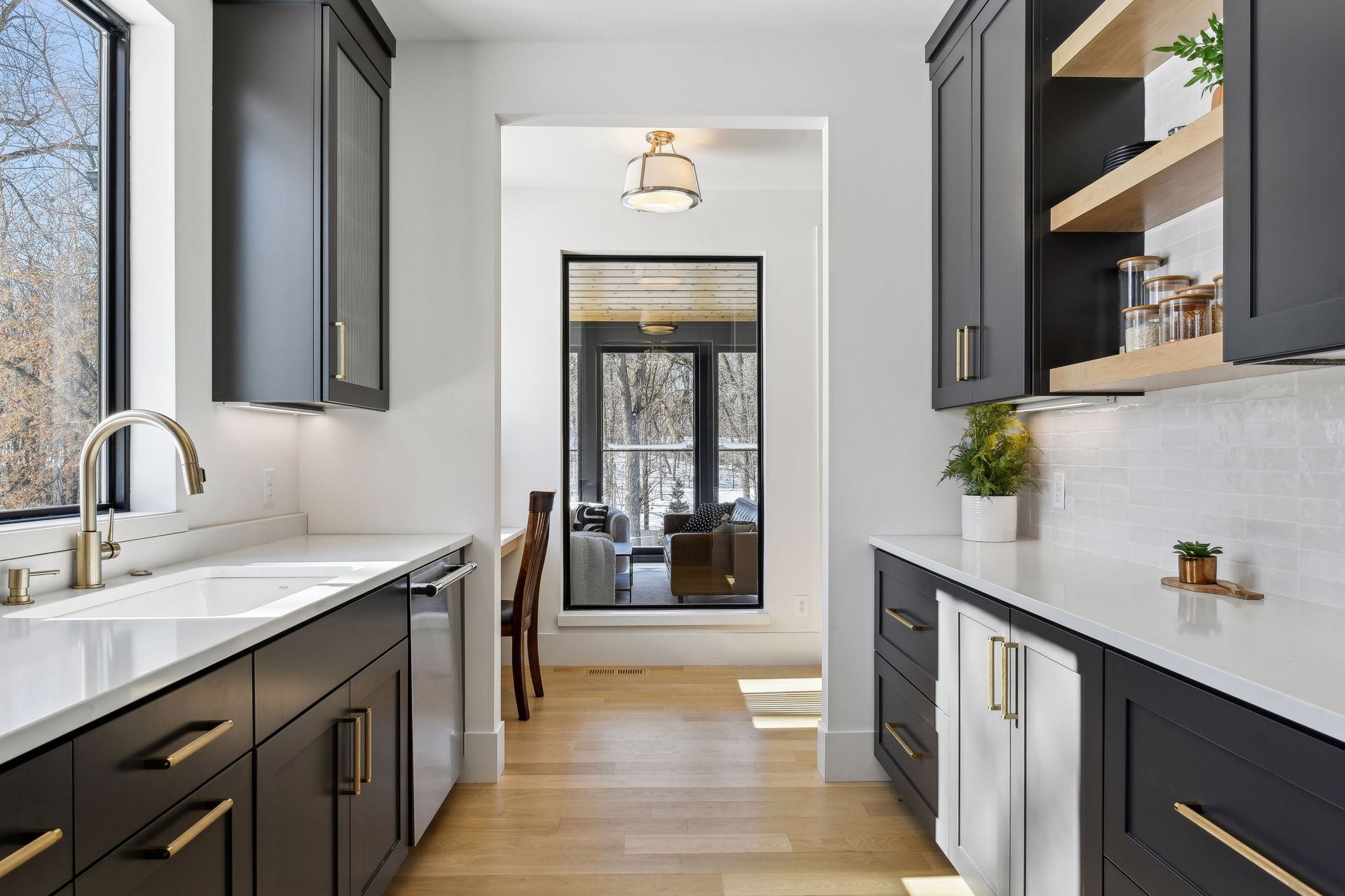 Butler's pantry with dark cabinetry, open shelving and brass hardware