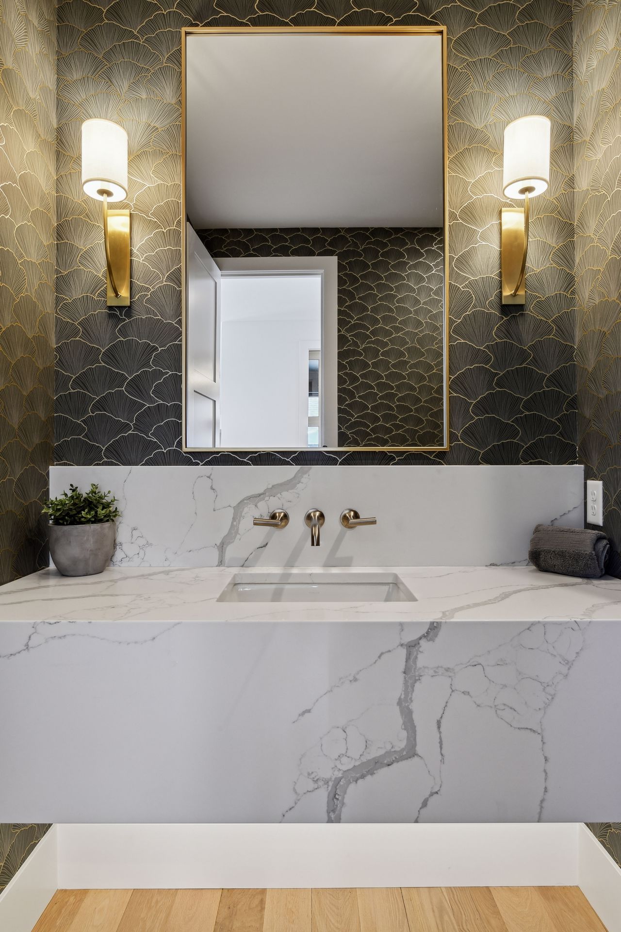 Designer powder room with marble vanity and gold wallpaper accents